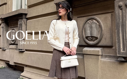 a lady in a white top, a brown wool pleated skirt, and a white tweed jacket