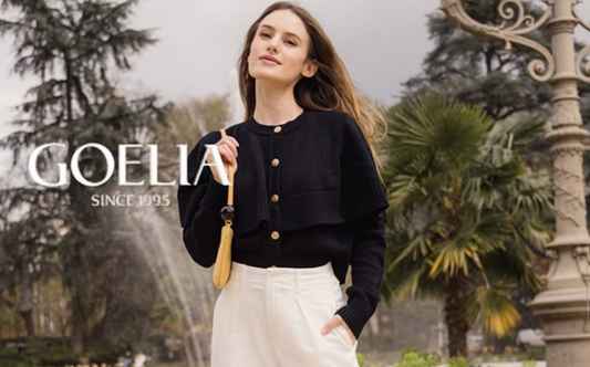a lady in a black cape cardigan and a pair of white jeans