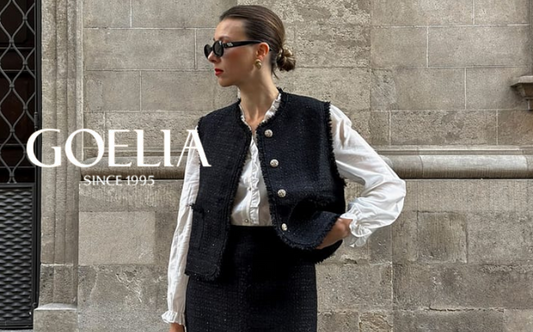 a lady in a white ruffle collared shirt, a black tweed vest and a black skirt